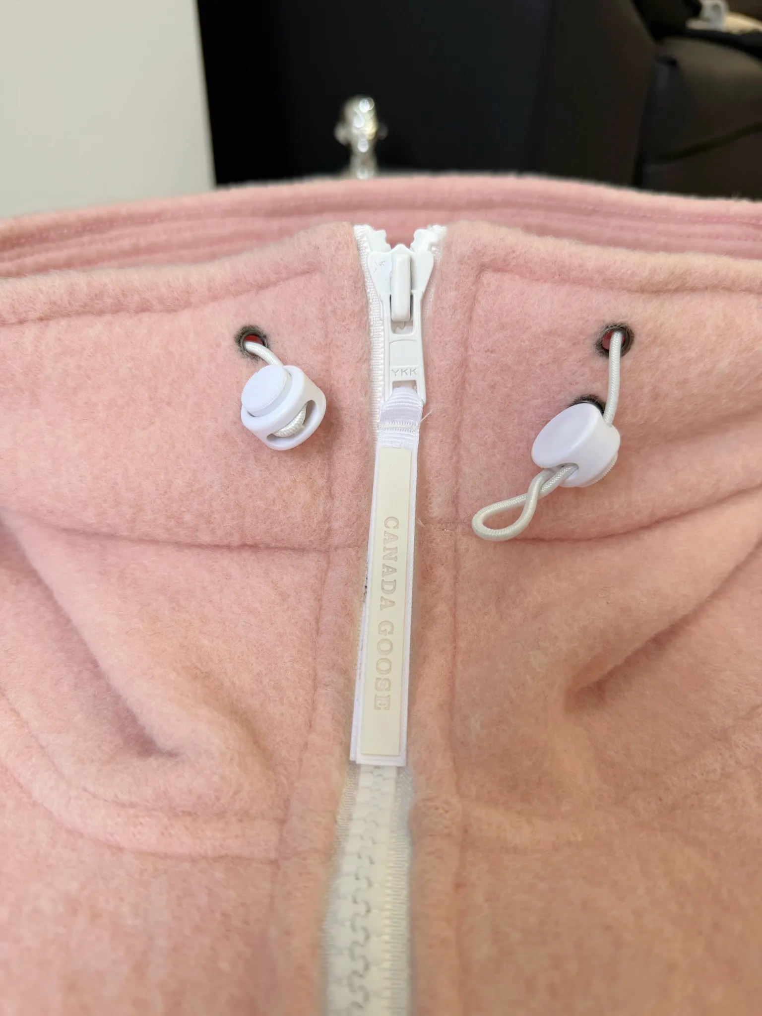 P660 Canada Goose Fleece Wool Badge Hooded Jacket Fabric selection: Wool fleece fabric blended with wool as the main body and a very small amount of spandex and polyester fiber. Wool is a core natural ingredient that provides unparalleled temperature regulation, antibacterial and anti-odor properties and a skin-friendly feel. The feeding of a small amount of spandex gives the fabric a certain degree of four-way elasticity, making it non-restrictive during daily activities. As the basis of fleece's structure, polyester fiber enhances the fabric's durability, wrinkle resistance and quick-drying properties. It contributes to the loft of the fleece and provides functions such as trapping air.  Detail 1: The sleeves and hem are closed with 2×2 ribbing. Its strong elasticity can closely fit wrists and waists of different thicknesses, forming an effective 'seal' to prevent cold wind from blowing back. It can still maintain its original shape after repeated stretching and use, and is not easy to loose and deform. And the ribbed cuffs can convey a sense of design and enhance the visual beauty.  Detail 2: The combination of hood design and elastic buckle improves warmth and windproof performance when wearing. Accessories: Customized elastic drawstring, elastic buckle, custom zipper pendant, custom armband Size: S M L Color: black gray coffee rice pink